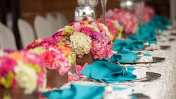 Una mesa adornada con servilletas color turquesa, centros de mesa florales y cubiertos.