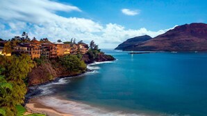 Un resort costero con villas frente a la playa, un litoral rocoso y una vista despejada del océano.
