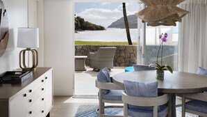 A modern room with a view of the sea, a dining area with blue chairs, a wicker chandelier, and a stone wall. - The Royal Sonesta Kaua'i Resort Lihue (Lihue)
