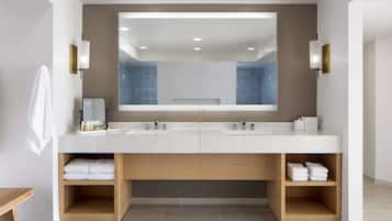 A modern bathroom with a double sink, a large mirror, and built-in shelves for towels.