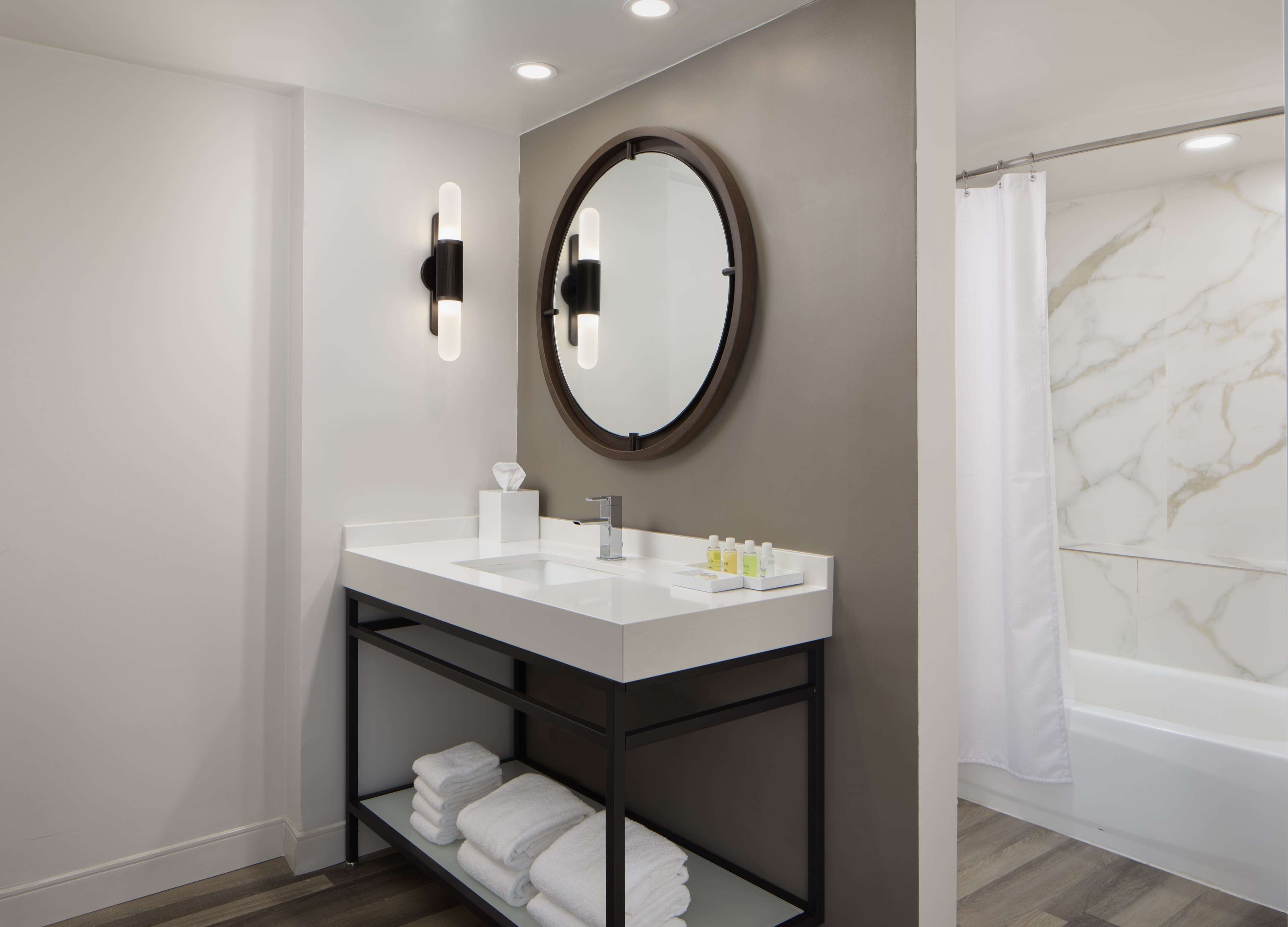 A modern bathroom with a double sink vanity, a large mirror, and a bathtub.