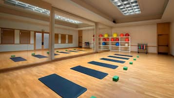 A spacious room with wooden flooring, large mirrors, and exercise mats.