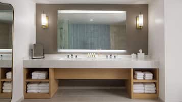 Une salle de bain moderne avec un grand miroir, deux lavabos et des étagères pour les serviettes.