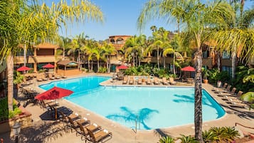 Una piscina al aire libre, sombrillas, sillones reclinables de piscina