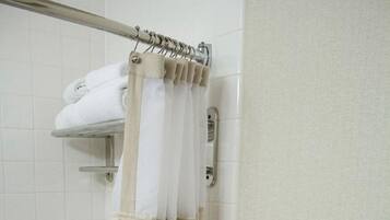 A bathroom with a shower curtain, a towel rack with folded towels, and a bathtub.