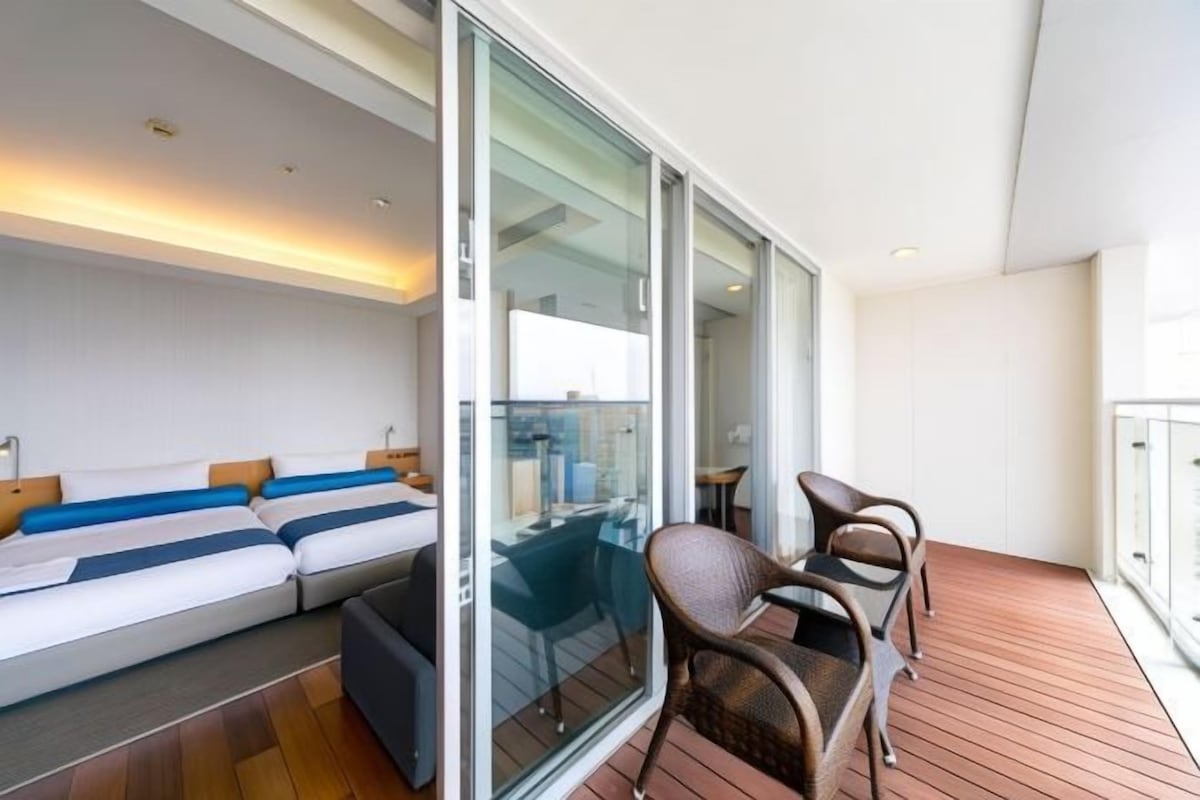 A balcony with a sofa, chairs, and a glass partition.