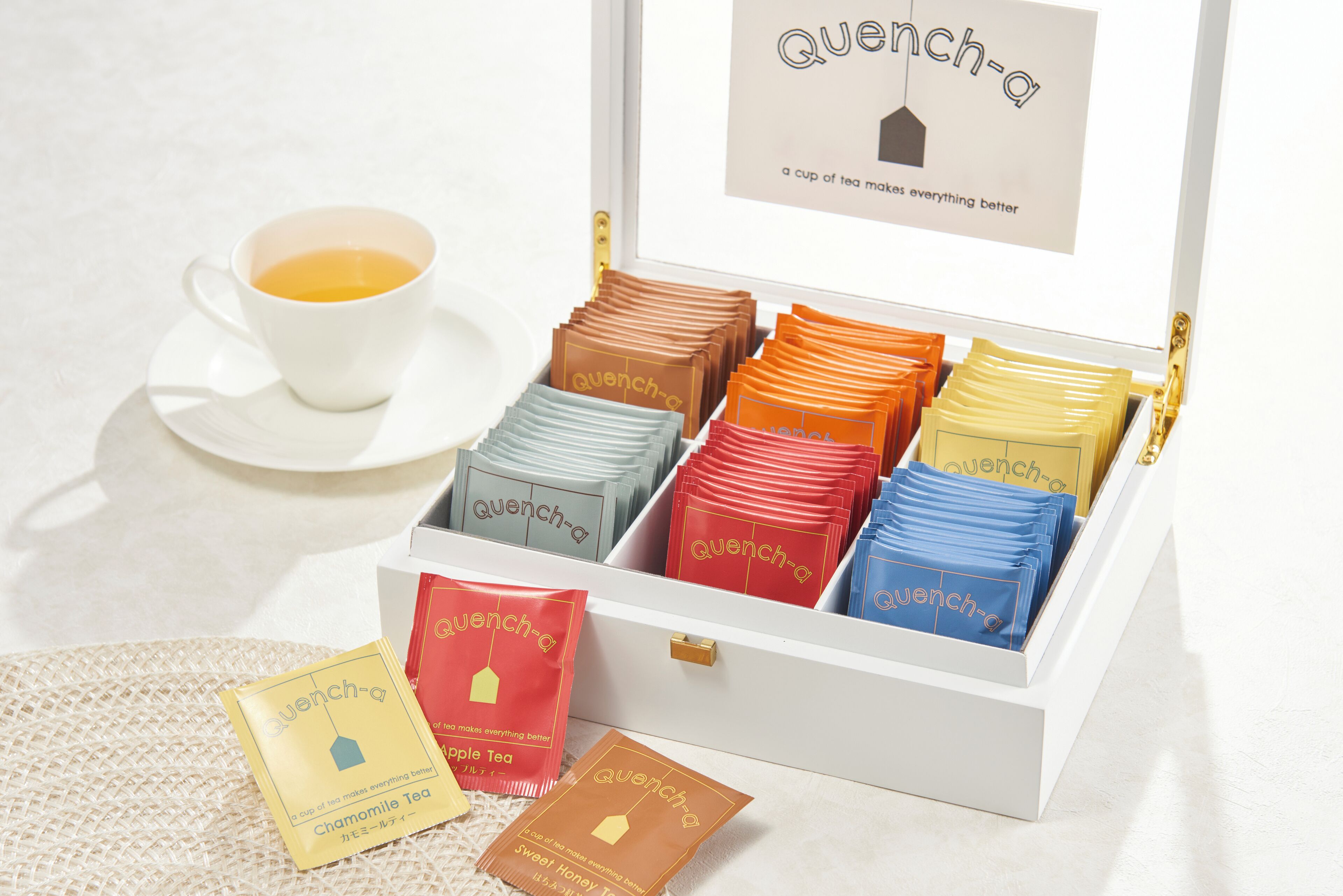 A white box with compartments containing tea bags labeled 'Quench-a'.
