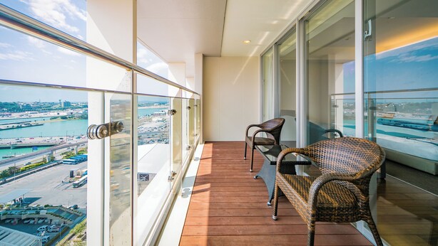 A balcony with wicker chairs and a view of a cityscape and water. - Naha Tokyu REI Hotel (Naha)