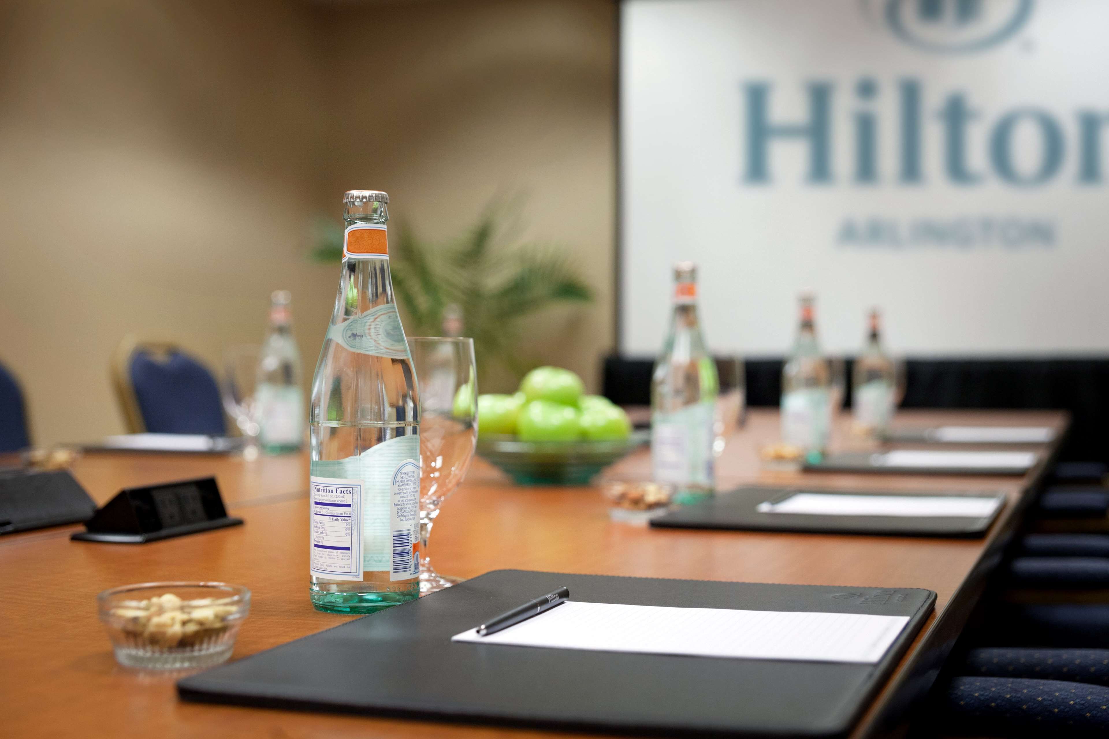 A conference table with water bottles, a glass, and a bowl of apples.