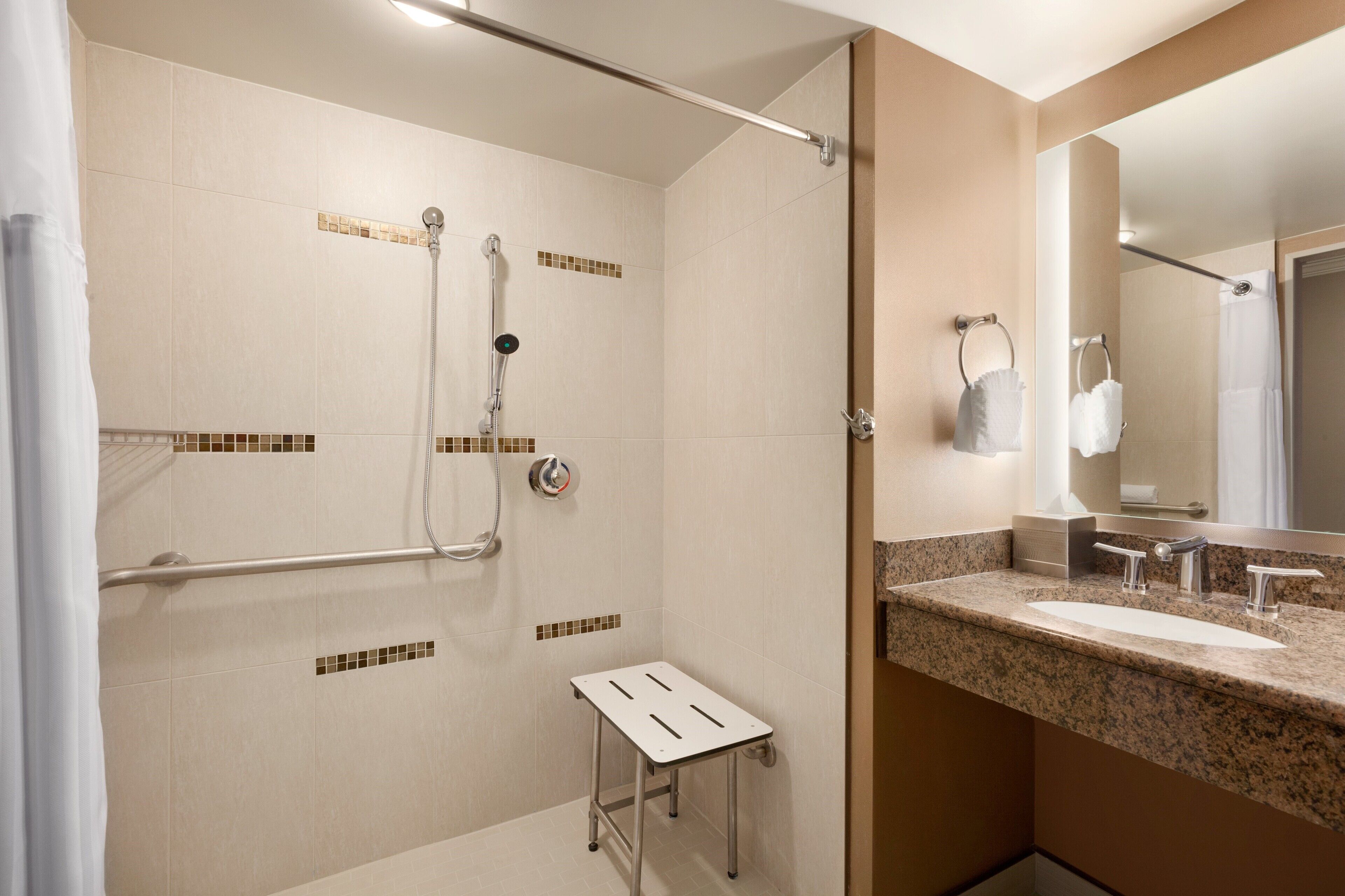 A modern bathroom with a shower, a sink, and a small step stool.