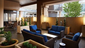 Un espace de détente moderne, avec des meubles en osier, des coussins bleus et des plantes en pot.