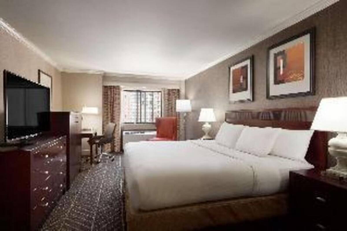 A hotel room with a bed, a television, a desk, and a chair.