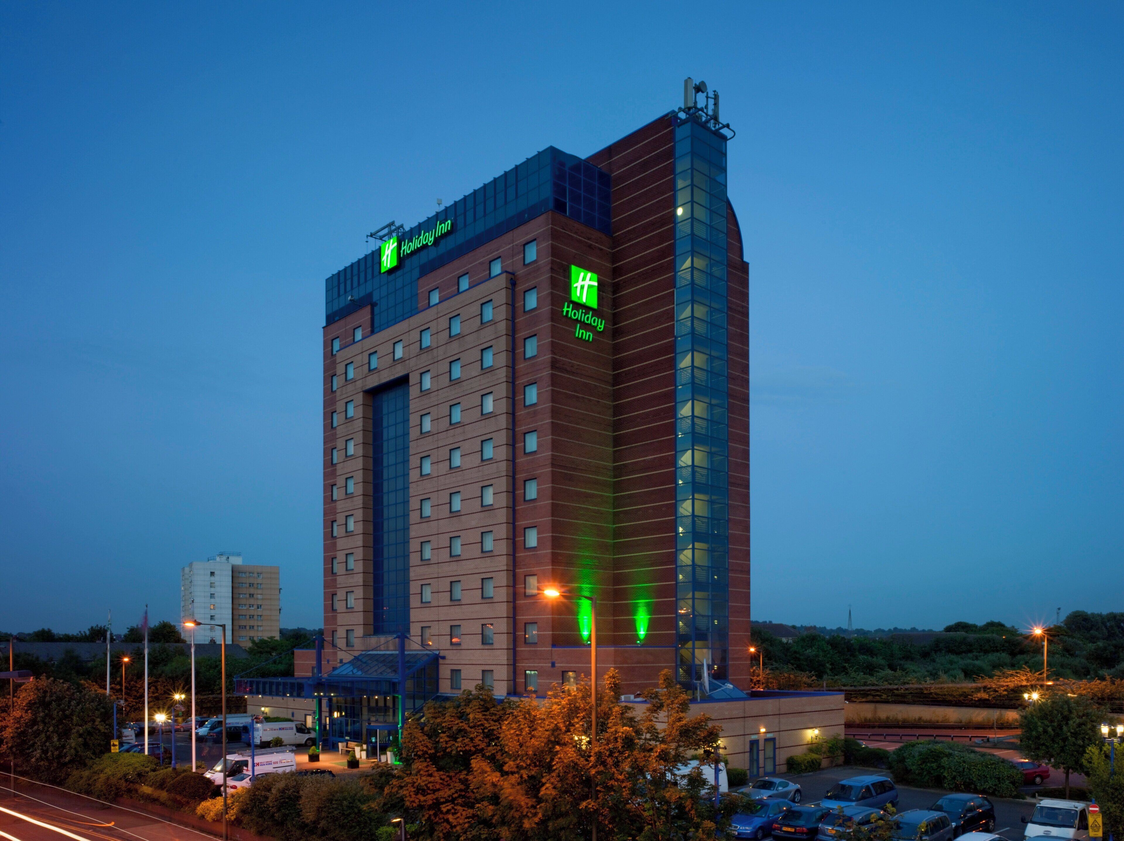 A Holiday Inn hotel with a prominent glass facade and a brick exterior.