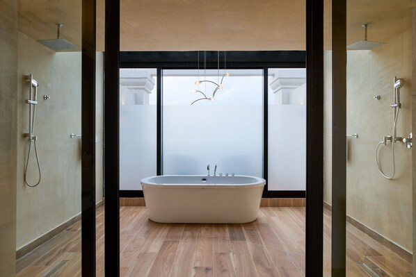 A modern bathroom with a freestanding bathtub, a glass shower enclosure, and a contemporary light fixture.