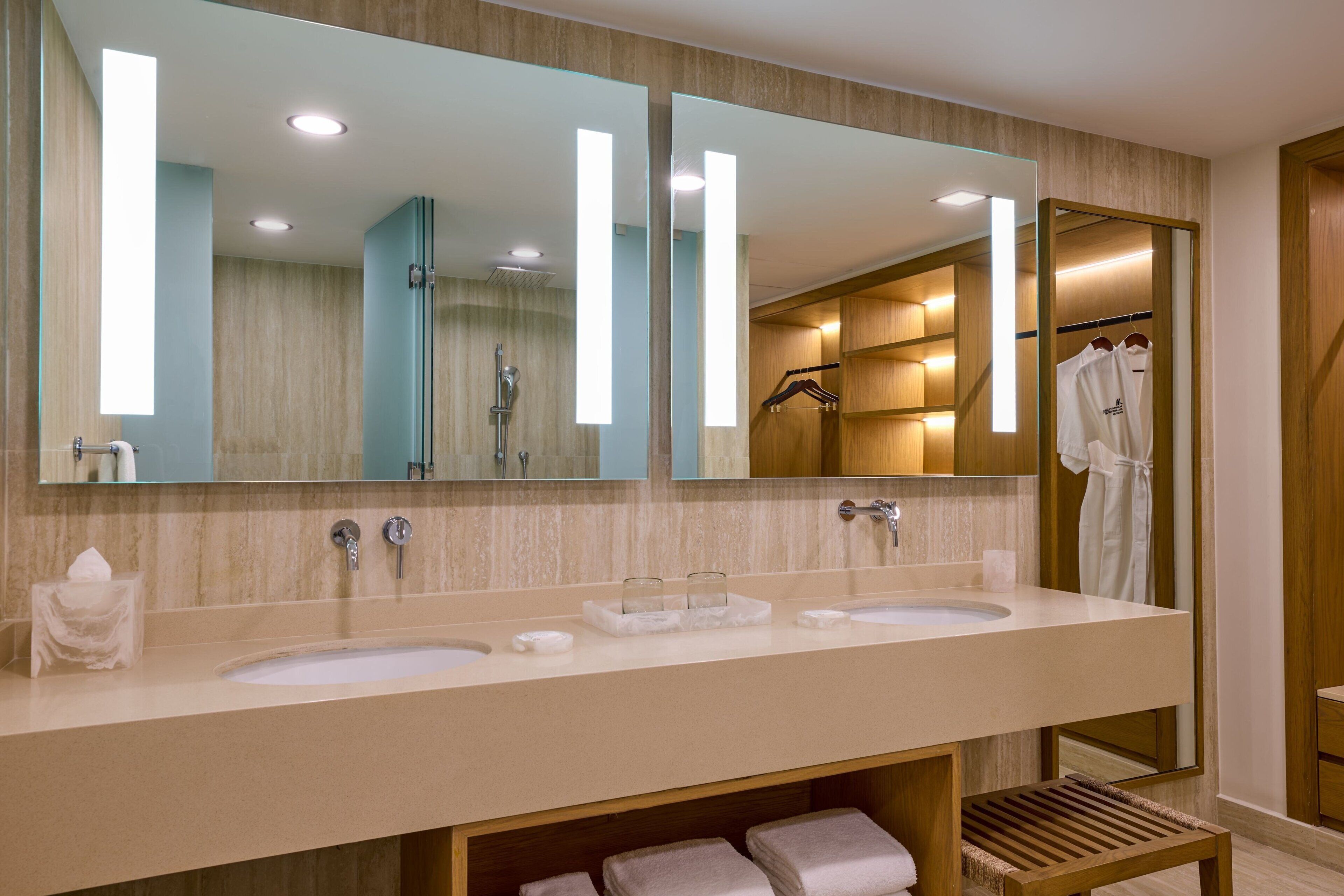 Ein modernes Badezimmer mit zwei Waschbecken, einem großen Spiegel und einem Kleiderhaken für Bademäntel.