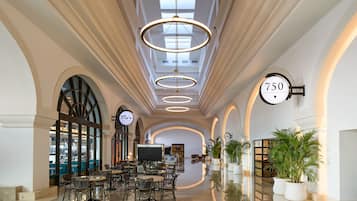 Eine großzügige Hotelhalle mit modernem Design, ausgestattet mit einer zentralen Sitzecke, einem großen Fernsehbildschirm und freiem Blick zum Himmel durch die Decke.