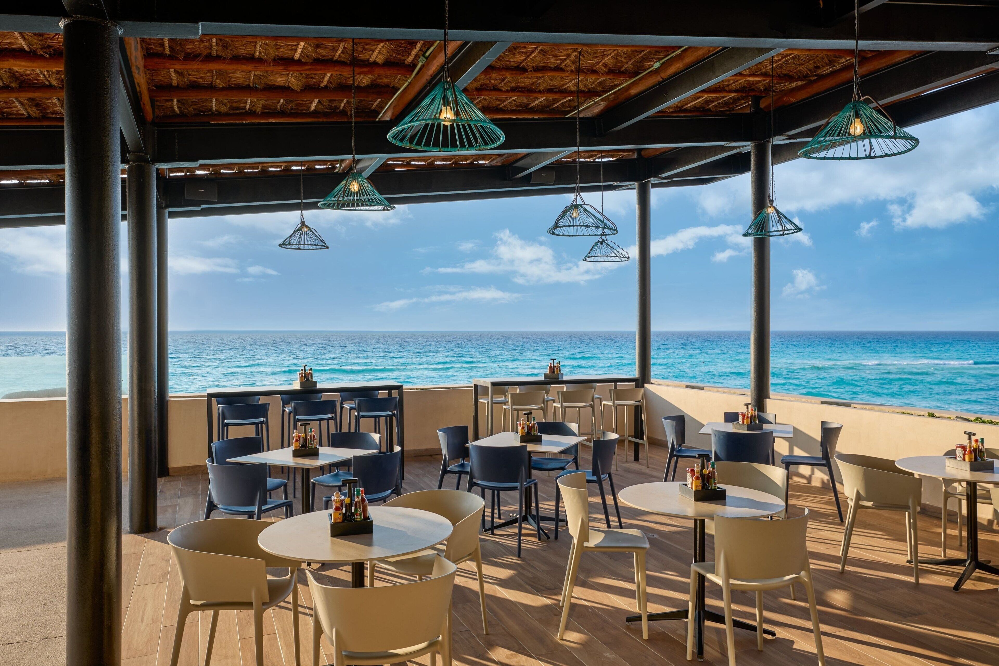 An outdoor seating area with tables and chairs, overlooking the ocean.
