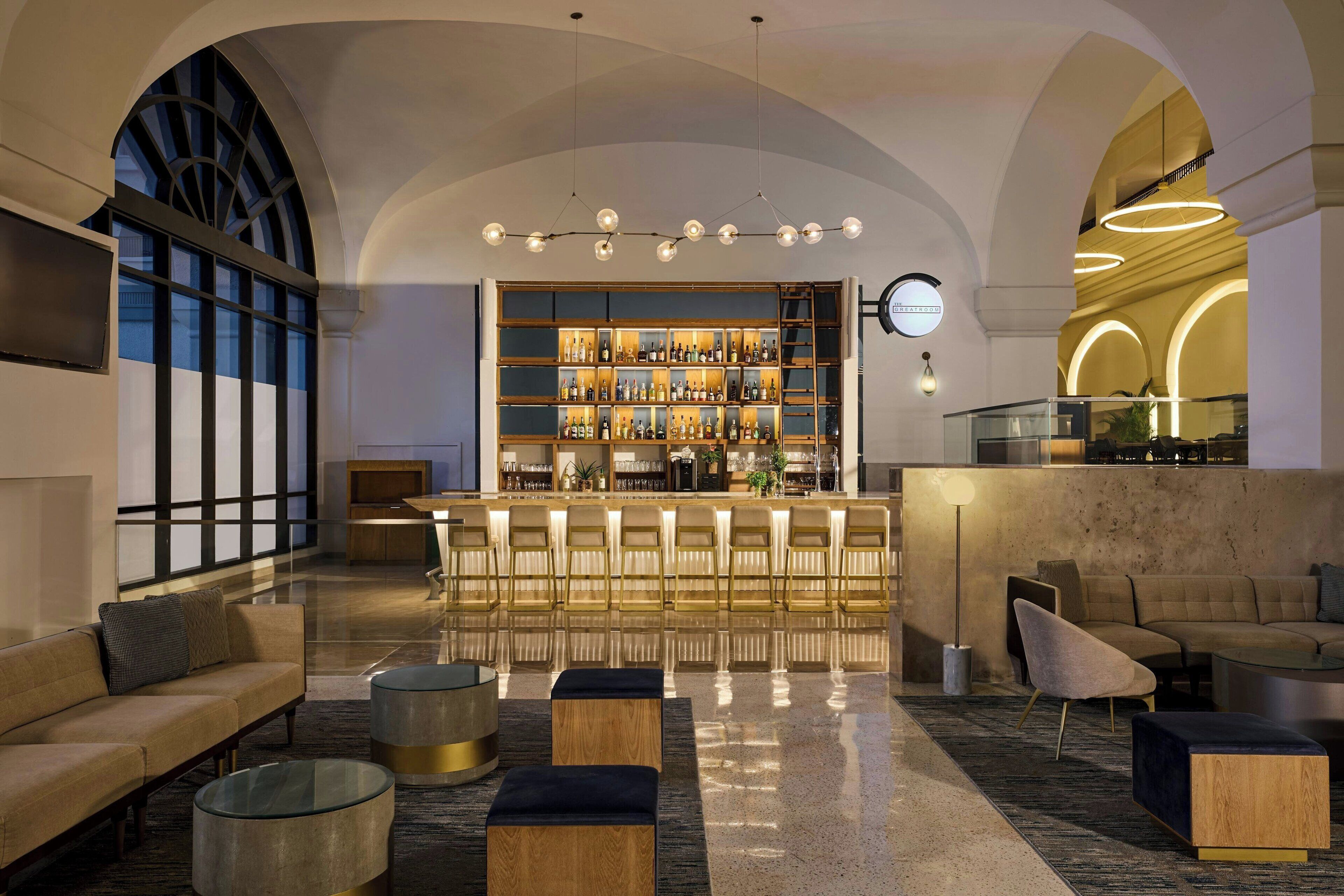 A modern bar area with a bar counter, seating, and a large display of bottles.