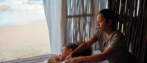 A massage therapy session in a room with a view of the beach.