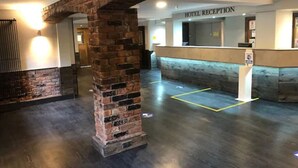 A hotel reception area with a brick pillar, a reception desk, and a sign indicating the reception. - Fairways Lodge & Leisure Club (Manchester)