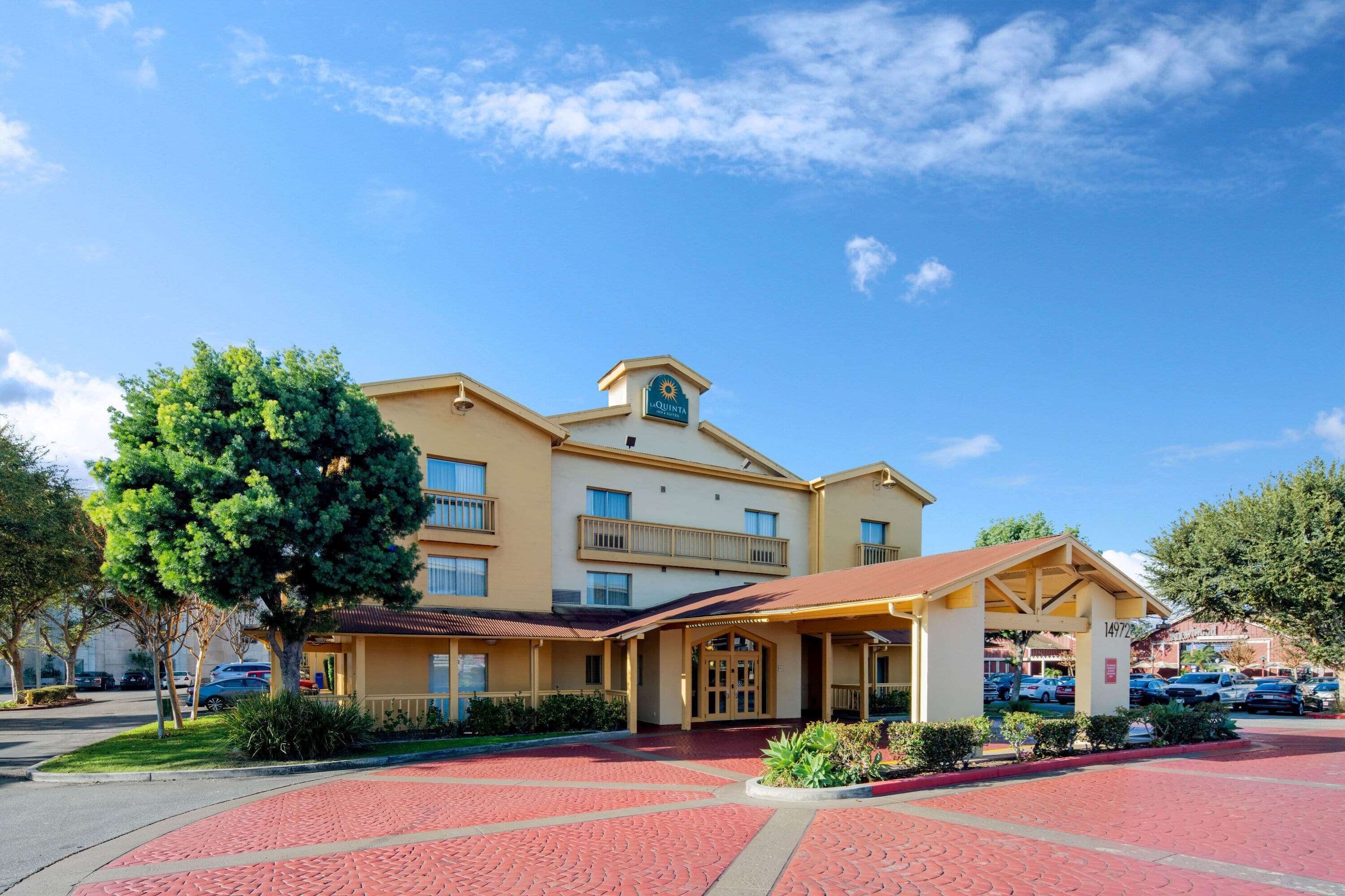A hotel with a central entrance, a covered patio area, and a parking lot.