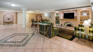 A spacious living area with a fireplace, a television mounted on the wall, and a dining table with chairs. - La Quinta Inn & Suites by Wyndham Irvine Spectrum (Irvine)