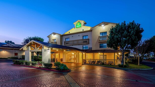 A hotel with a prominent sign, a covered entrance, and a paved driveway. - La Quinta Inn & Suites by Wyndham Irvine Spectrum (Irvine)