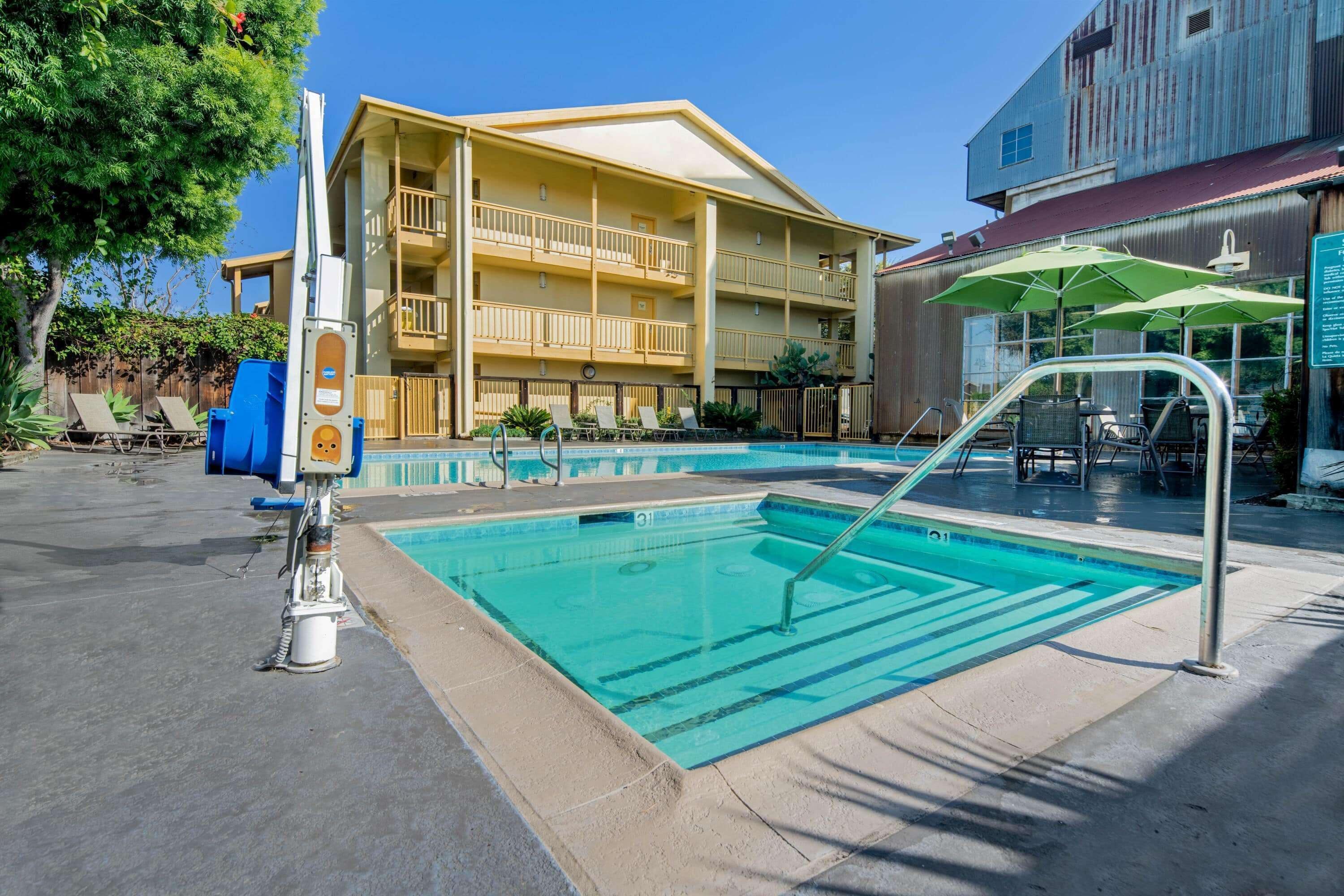 A pool area with a lifeguard chair, lounge chairs, and a building with a balcony.