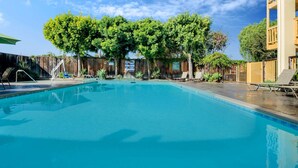 A swimming pool with clear blue water, surrounded by trees and a wooden fence. - La Quinta Inn & Suites by Wyndham Irvine Spectrum (Irvine)