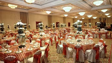 A large banquet hall with round tables, chairs, and floral centerpieces.