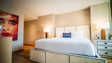 A modern hotel room with a large bed, two bedside lamps, a nightstand with a lamp, and a large abstract painting on the wall.