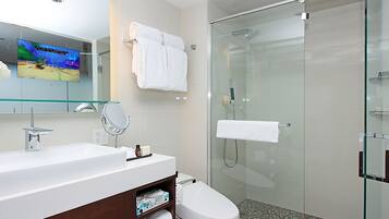 Un baño moderno con cabina de ducha de vidrio, un lavabo blanco y un espejo grande.