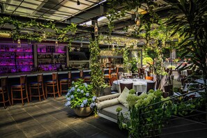 An indoor restaurant with a bar area, seating, and greenery. - J House Greenwich (Riverside)