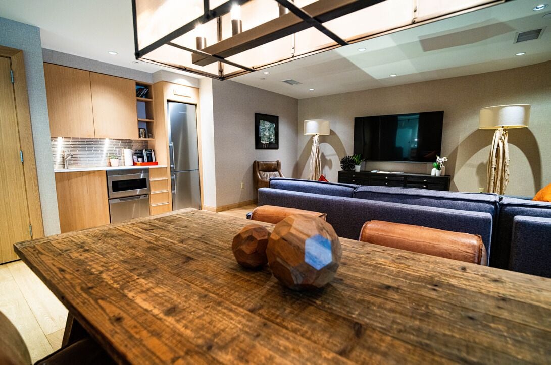 A modern kitchen with wooden cabinets, a dining table with a rustic finish, and a seating area with a sofa and chairs.
