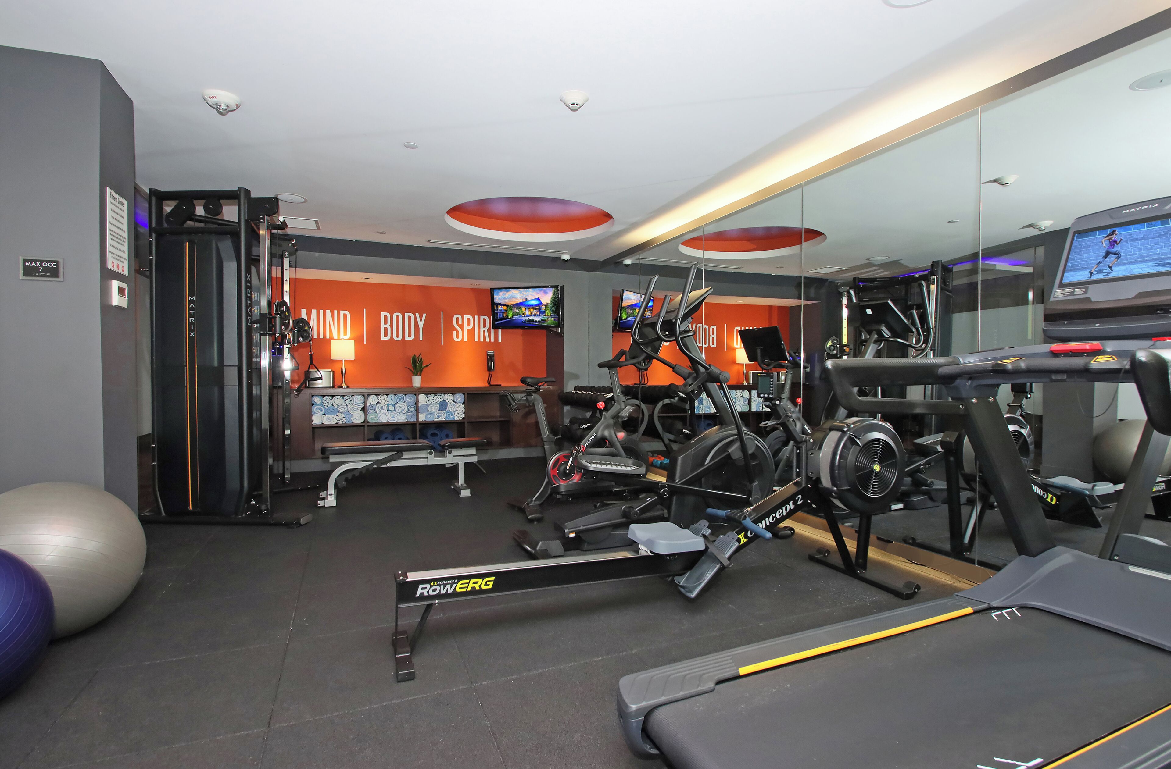 A gym with exercise equipment, a treadmill, and a wall with motivational words.