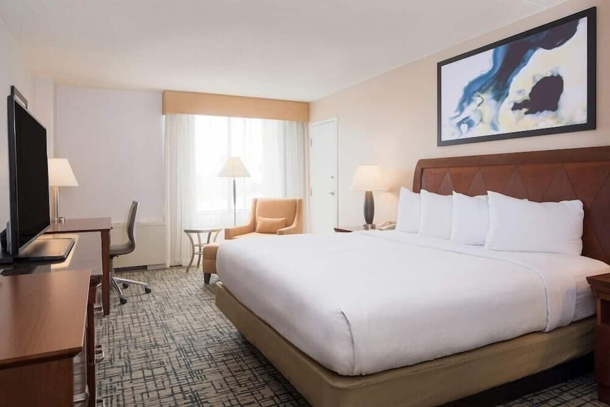 A hotel room with a large bed, a desk with a computer, a chair, and a television.