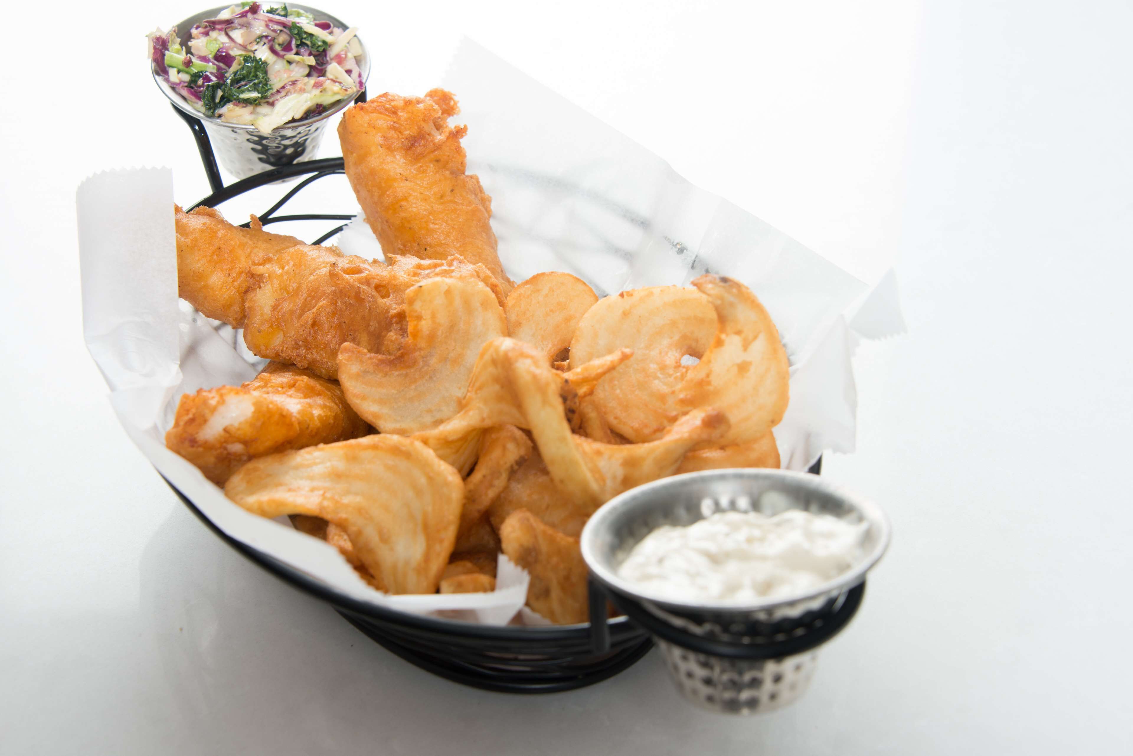 A basket of fried food with a side of coleslaw and a small bowl of sauce.