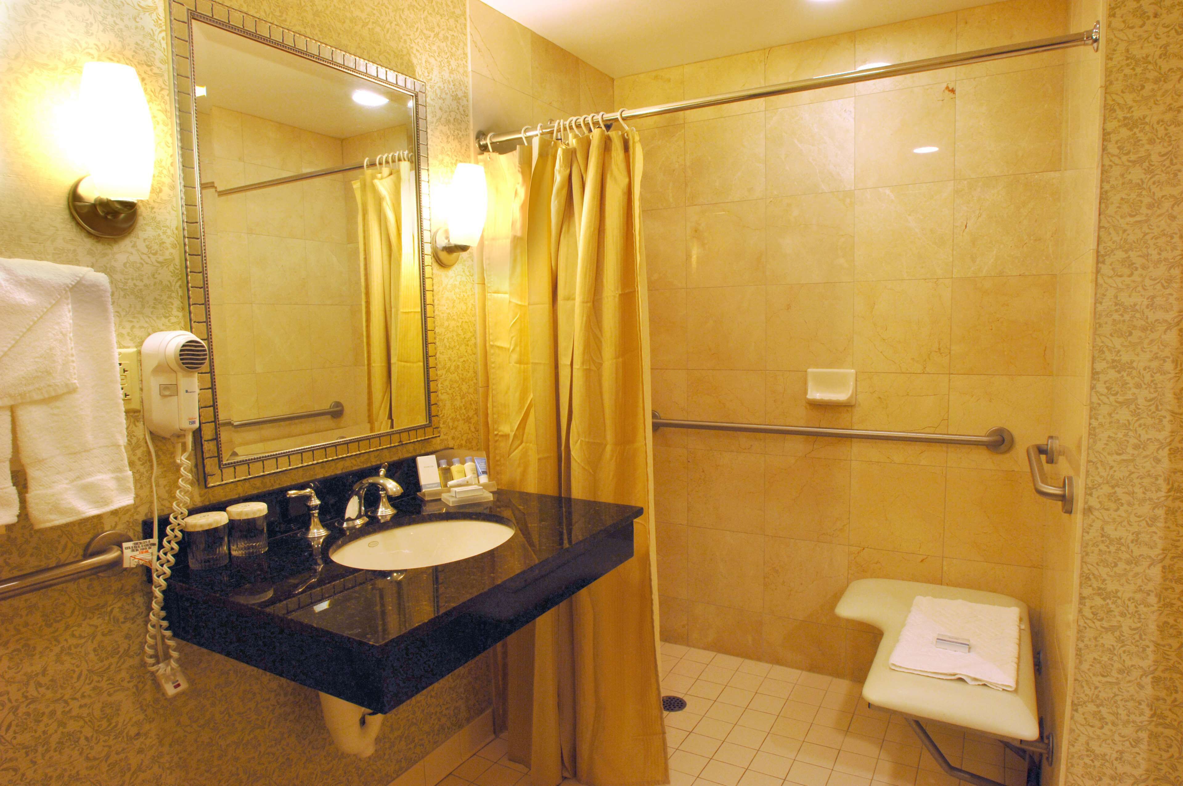 A bathroom with a sink, mirror, and shower area.
