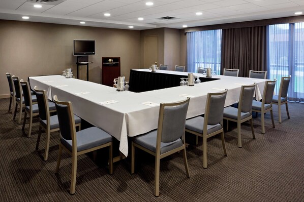 A conference room with a long table, chairs, a podium, and a television. - DoubleTree by Hilton Hotel Syracuse (East Syracuse)