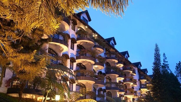 A multi-story hotel with balconies, surrounded by trees and well-lit pathways.