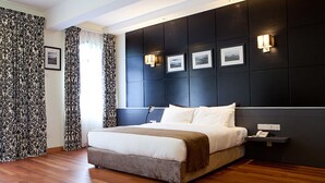 A modern bedroom with a large bed, dark headboard, and bedside lamps.