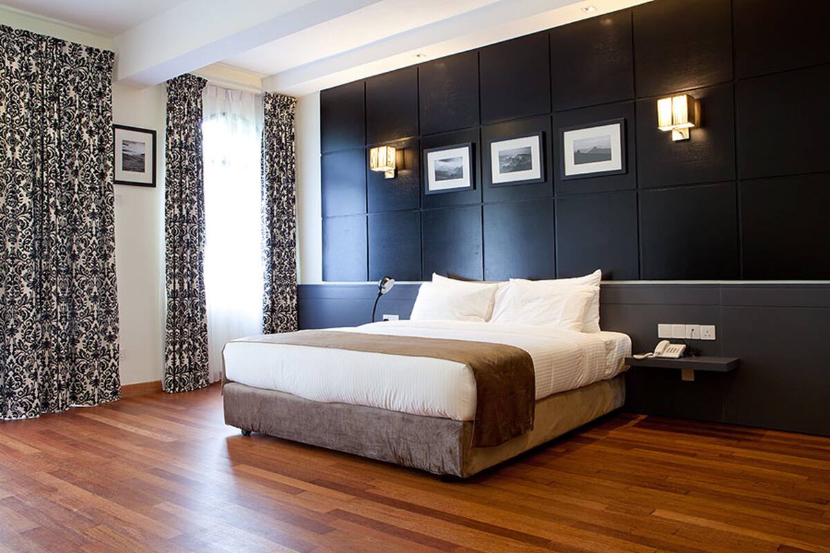 A modern bedroom with a large bed, dark headboard, and bedside lamps.