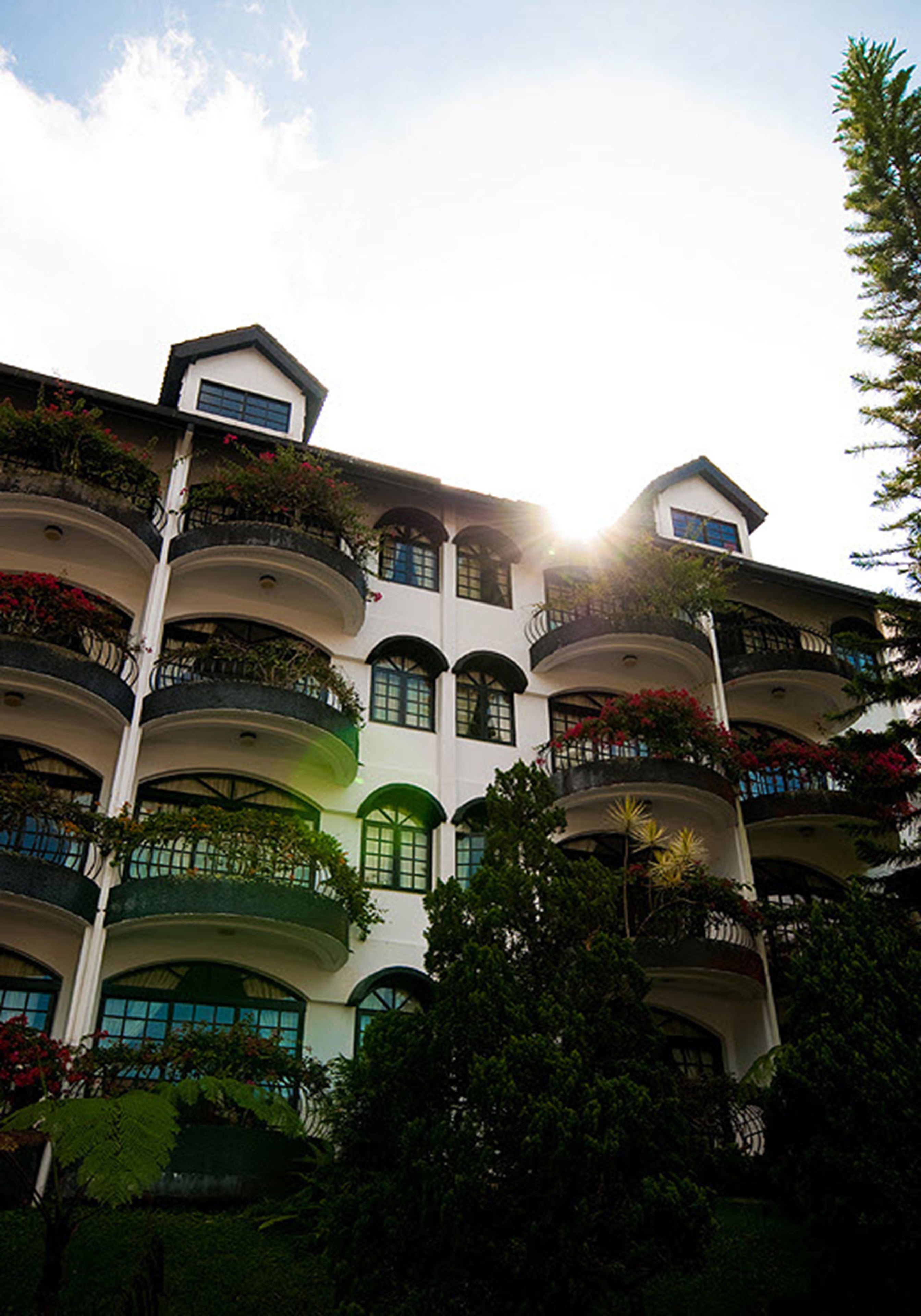 A multi-story hotel with balconies, each with plants and flowers.