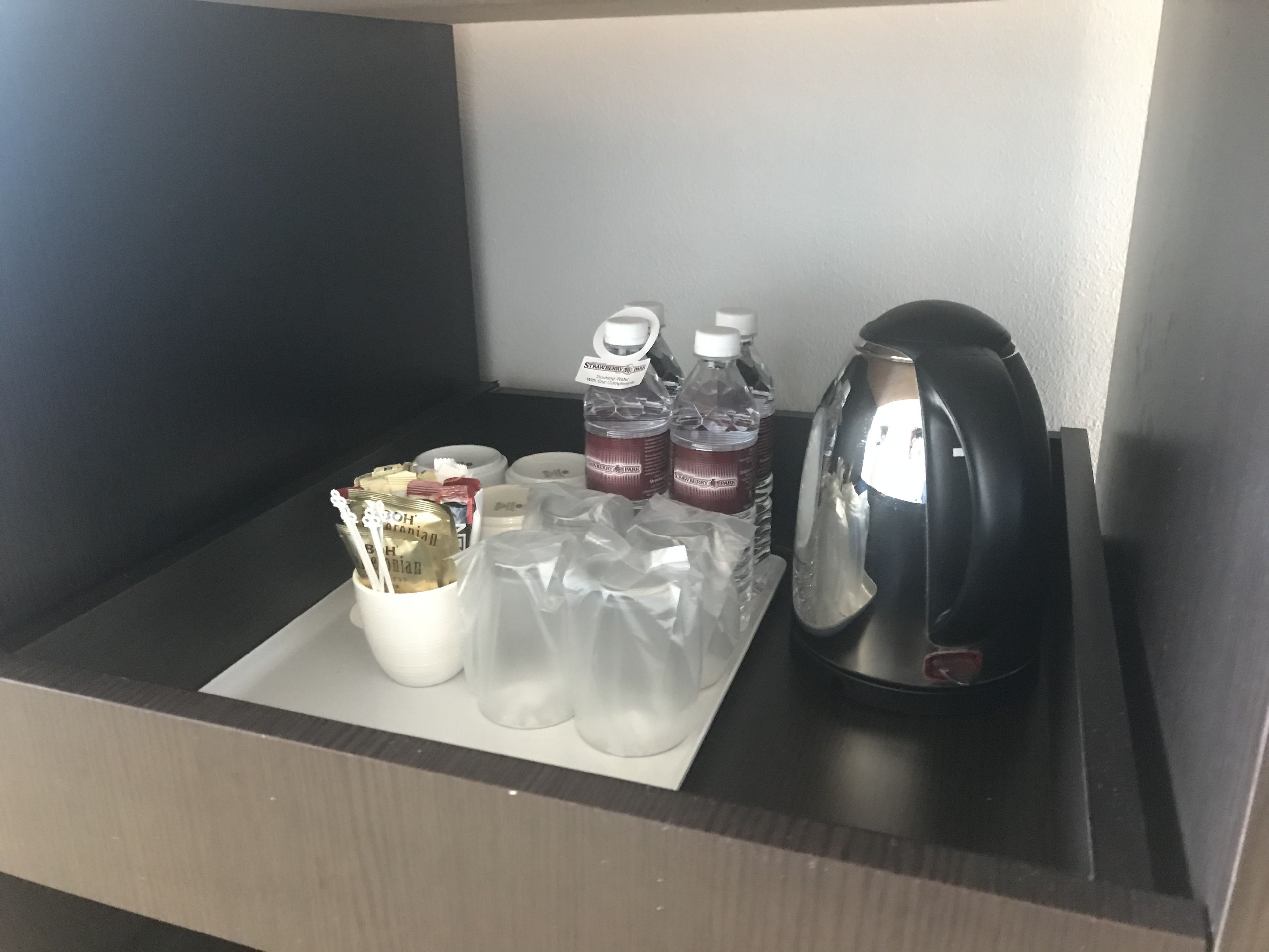 A minibar with a coffee maker, bottled water, and snacks.