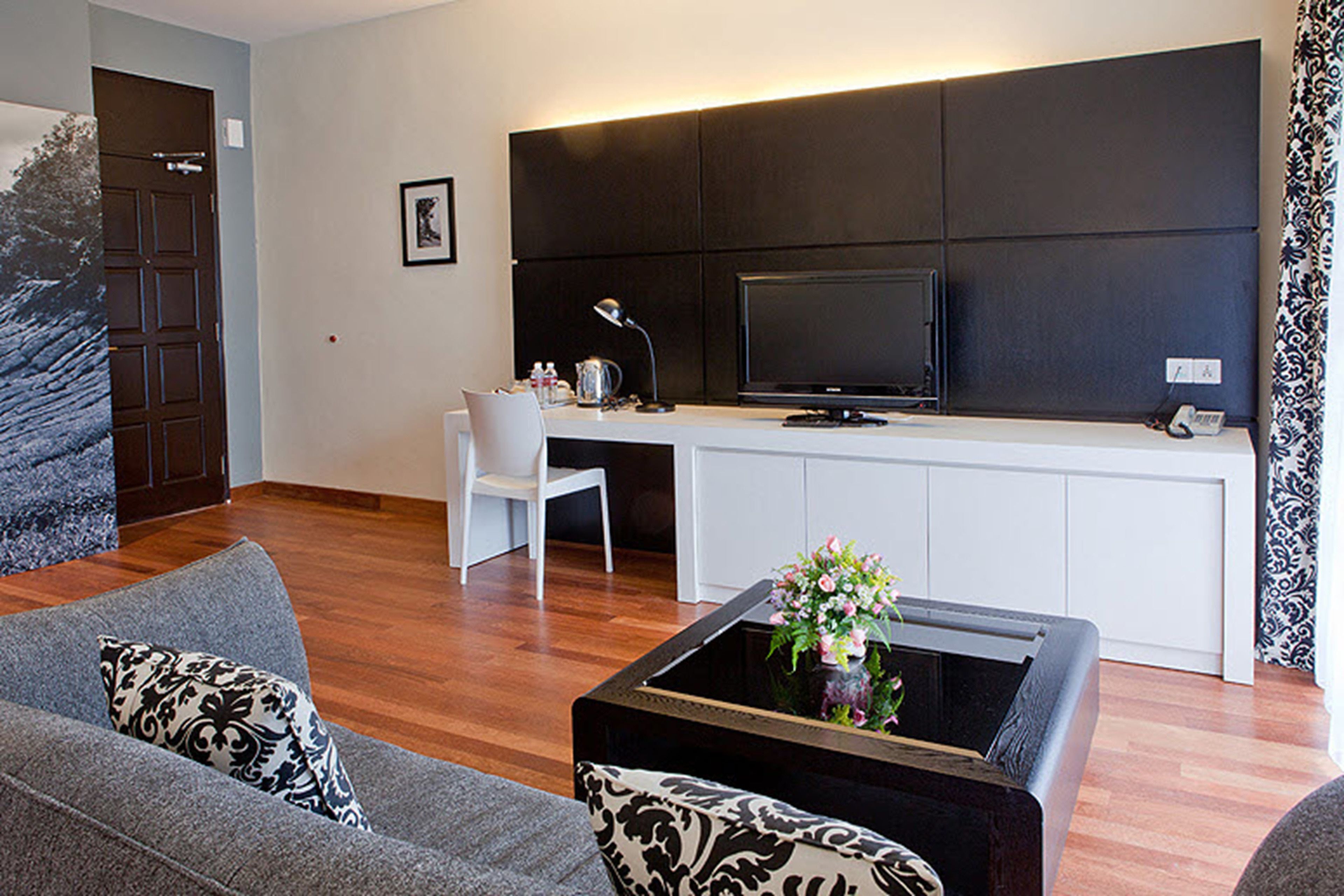 A modern living room with a sofa, coffee table, TV, and a white chair.