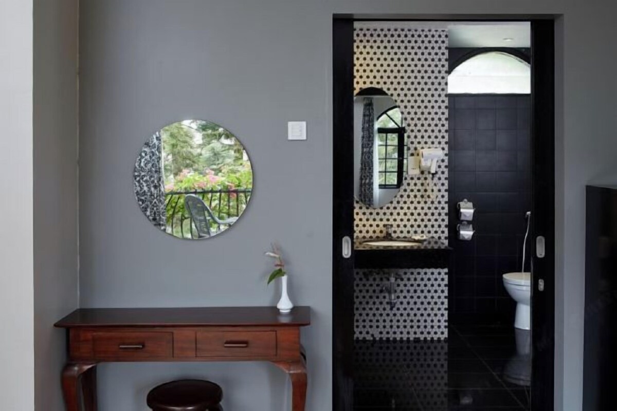 A bathroom with a black tiled wall, a white toilet, and a sink with a patterned backsplash.