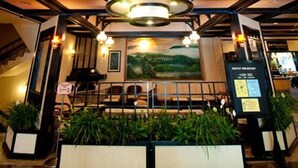 A lobby with a large circular ceiling light, a reception desk, and potted plants.