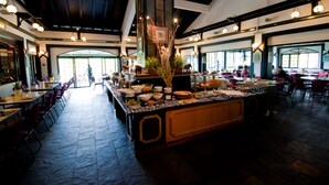A spacious restaurant with a long counter, multiple tables, and a high ceiling with exposed beams.