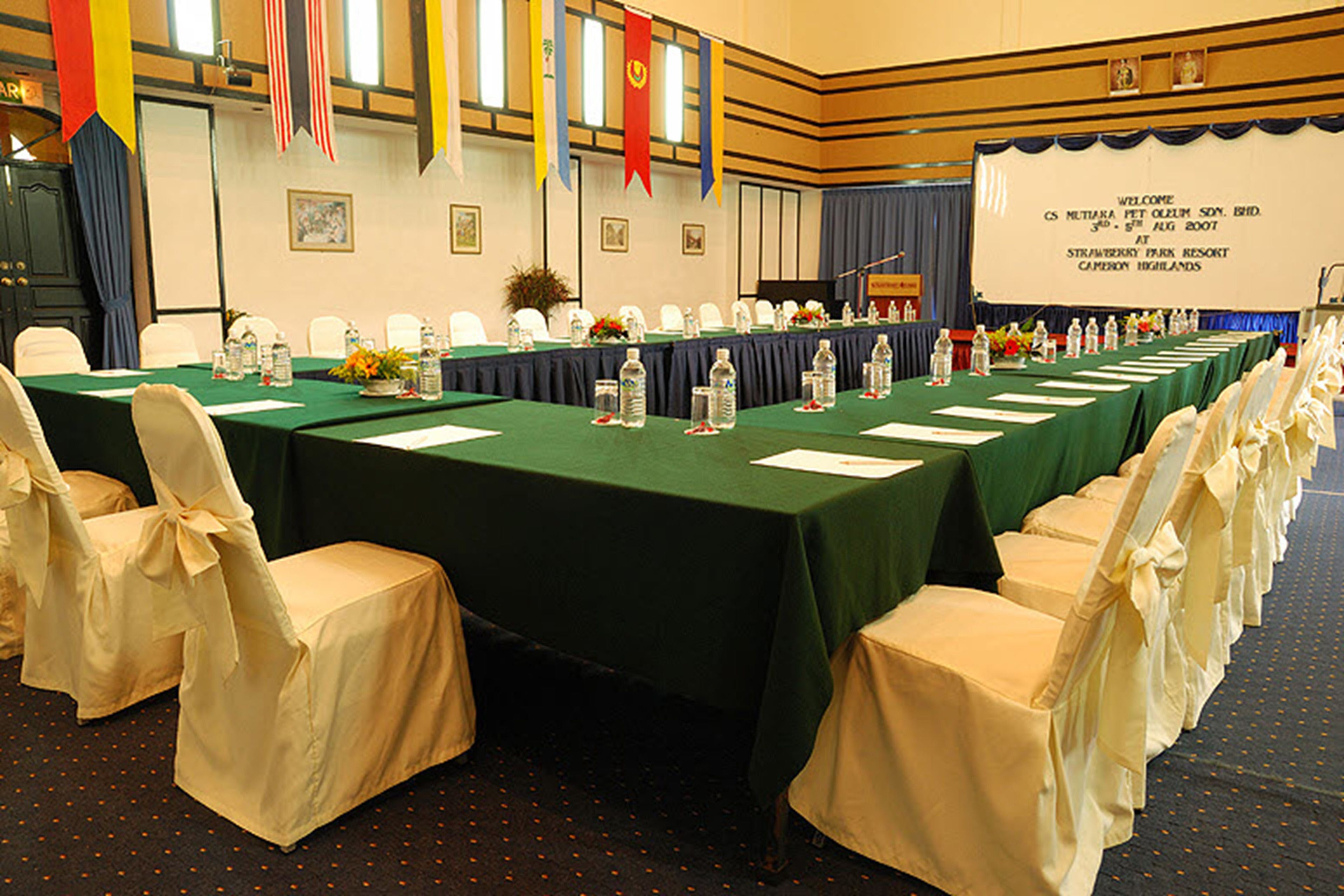 A conference room with a long table, chairs, and a screen displaying a welcome message.