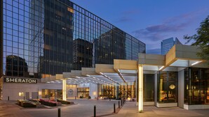 A Sheraton hotel entrance with a glass facade, outdoor seating, and a well-lit walkway.